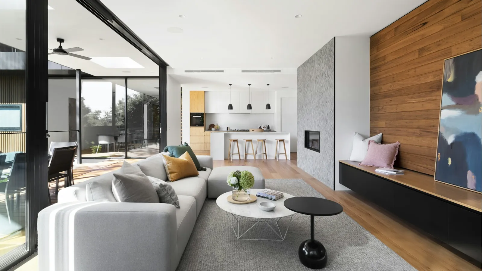 Salón luminoso con cocina abierta, madera y grandes ventanales
